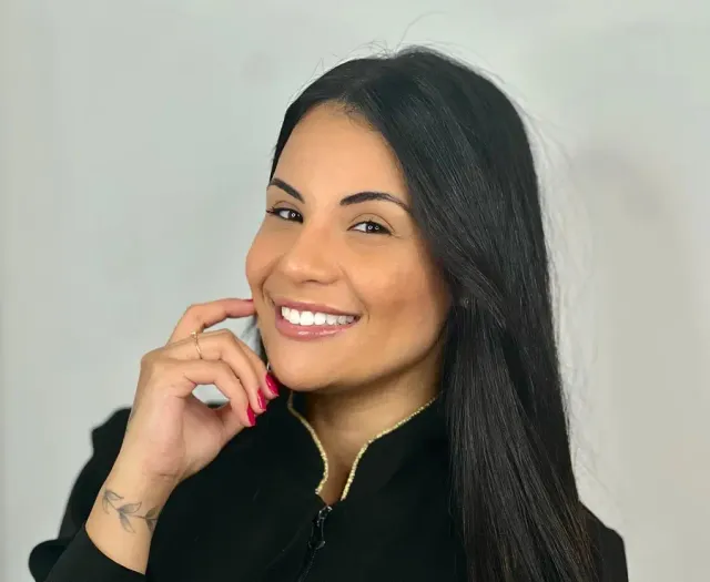 Thuany Oliveira sorrindo, de uniforme preto